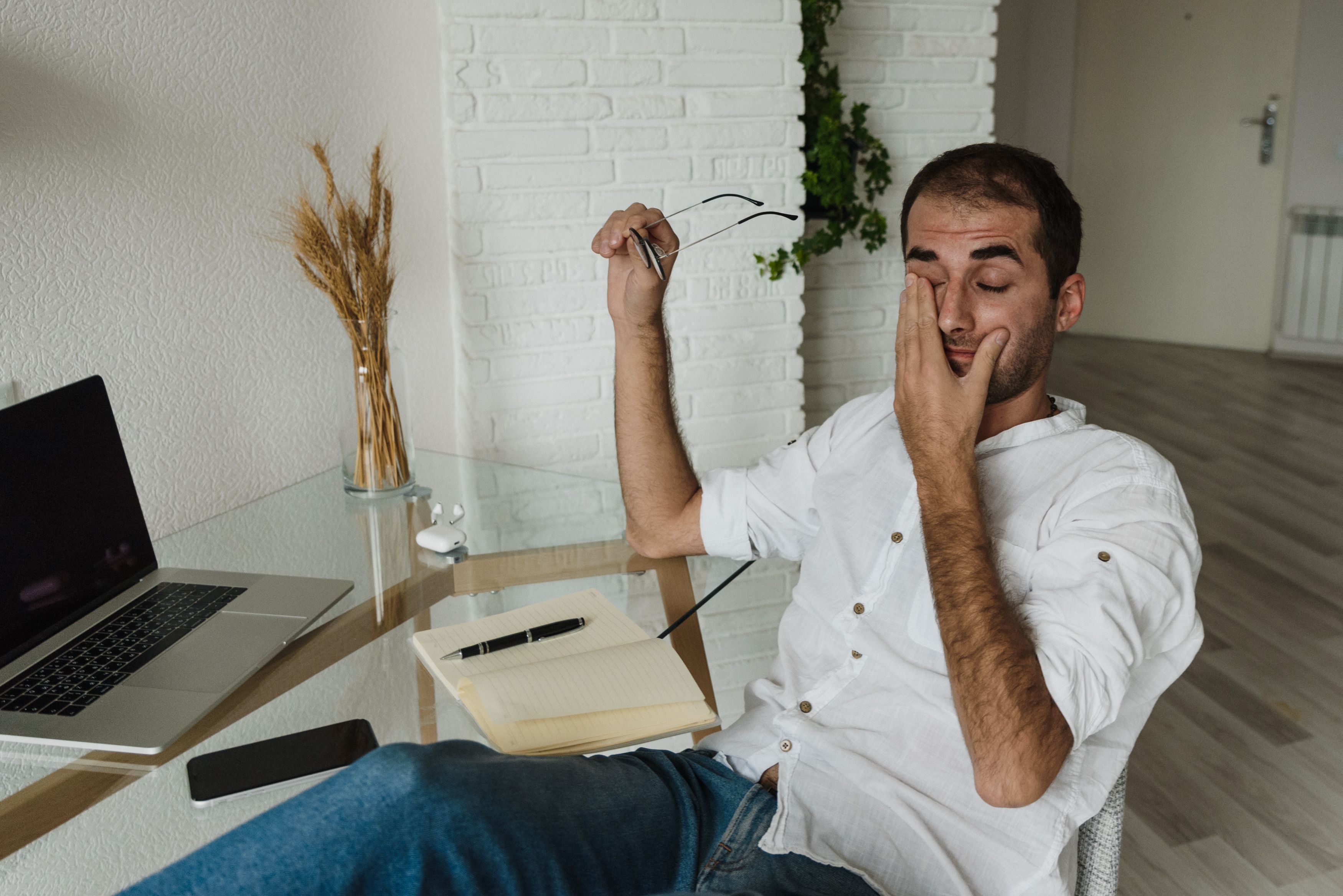 Professional experiencing digital eye strain while working on a laptop for long hours.